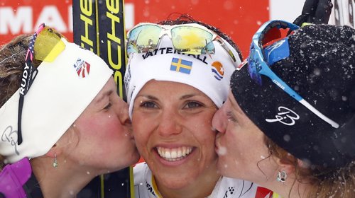 Sveriges Charlotte Kalla (midten) får kyss fra sølvvinner, USAs' Jessica Diggins (venstre) og bronsevinner fra USA (høyre) Caitlin Gregg på podiet.